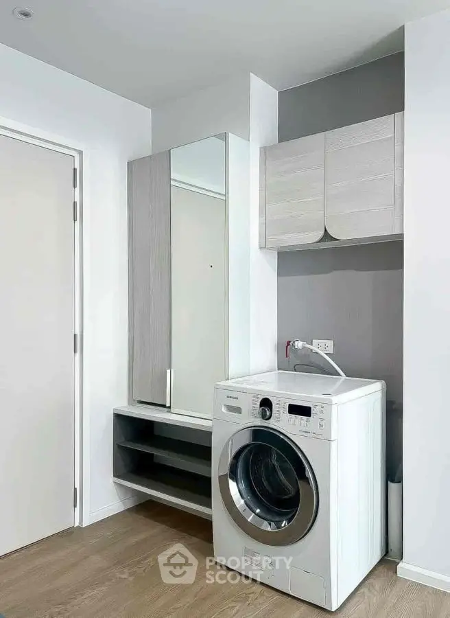 Modern laundry room with washing machine and storage cabinets in sleek design.