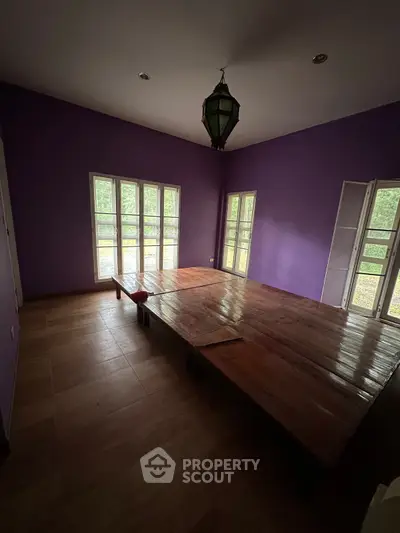 Spacious room with purple walls and large windows, featuring a unique wooden platform.