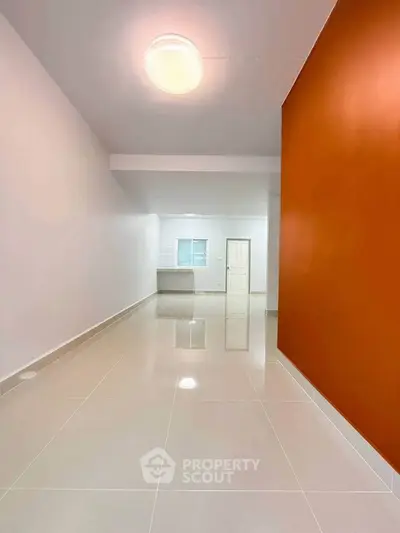 Spacious modern interior with glossy tiled floors and vibrant accent wall, perfect for stylish living.