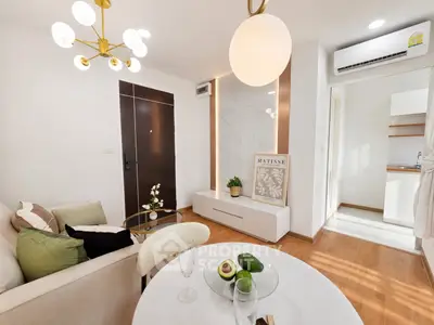 Modern living room with elegant decor and open kitchen layout, featuring stylish lighting and cozy seating area.