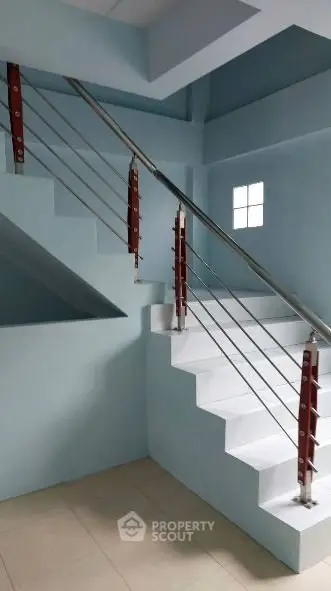 Modern staircase with sleek metal railing in a contemporary building interior.