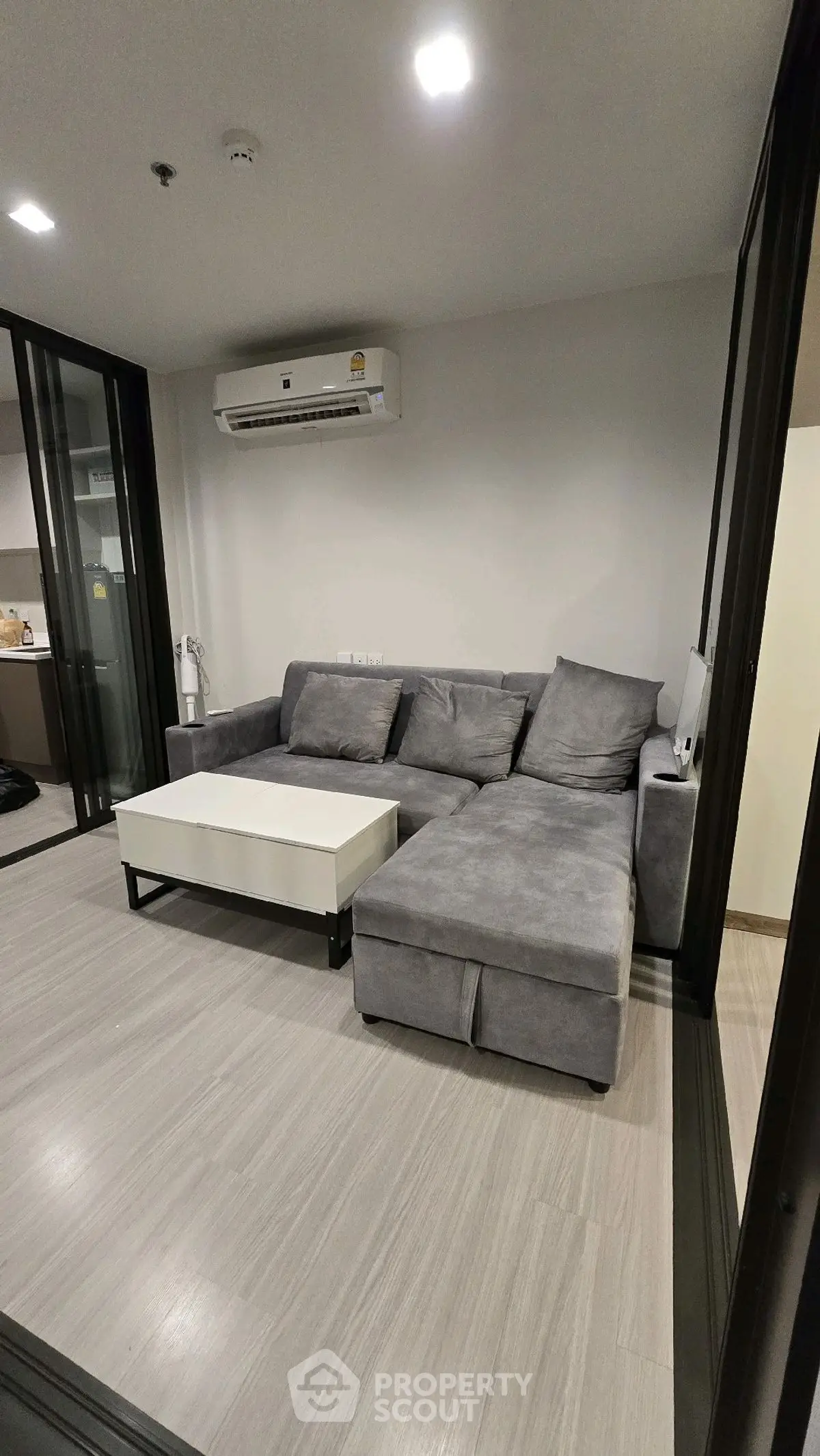 Modern living room with gray sectional sofa and sleek coffee table in stylish apartment.