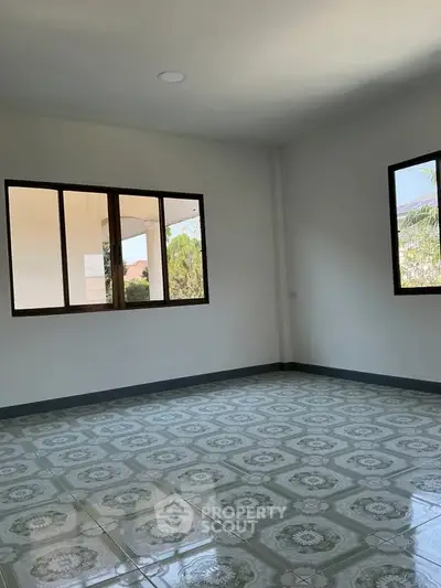 Spacious empty room with large windows and decorative tiled flooring