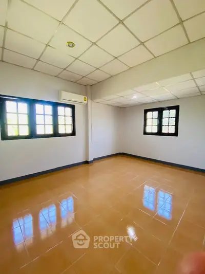 Spacious empty room with tiled floor and large windows, perfect for customization.