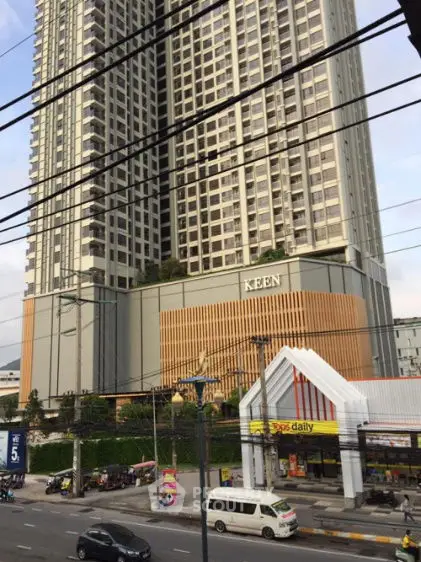 Modern high-rise building with retail space on busy street in urban area.
