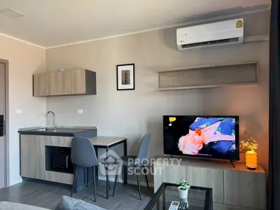 Modern living room with sleek furniture, wall-mounted TV, and compact kitchen area.