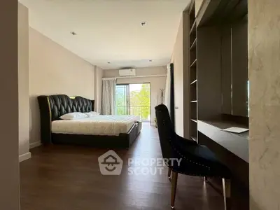 Spacious bedroom with elegant decor and large window offering natural light and garden view.