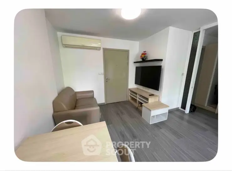 Modern living room with sleek furniture and wall-mounted TV in a cozy apartment.