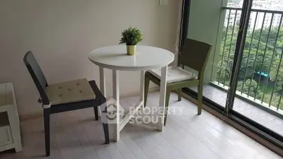 Cozy dining nook with round table and chairs near balcony with lush green view.