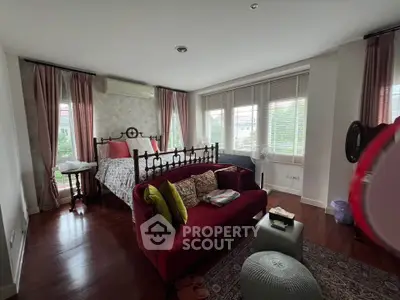 Charming bedroom with elegant decor and large windows offering natural light and garden views.