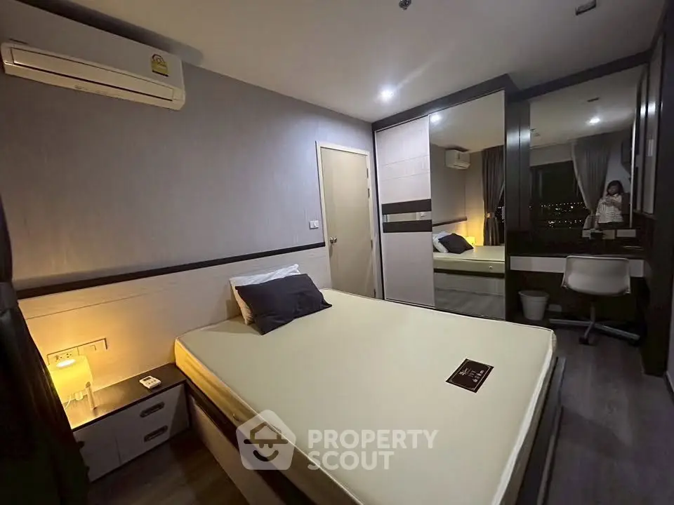 Modern bedroom with sleek design, featuring a large mirror and ambient lighting for a cozy atmosphere.