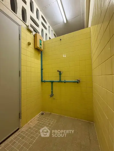 Unique industrial-style bathroom with yellow tiles and exposed piping, perfect for creative renovation.