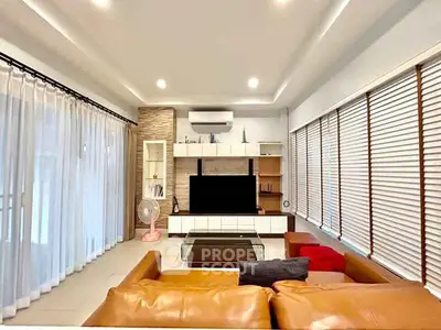 Spacious modern living room with leather sofa and large windows for natural light.