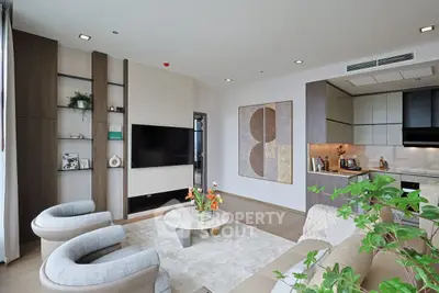 Modern living room with stylish decor and open kitchen layout, featuring elegant furniture and contemporary design.