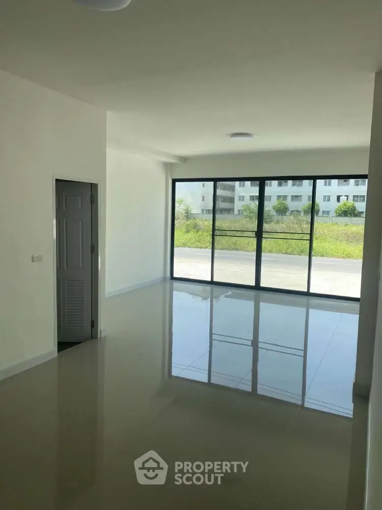 Spacious modern living room with large windows and glossy floors in a bright apartment.