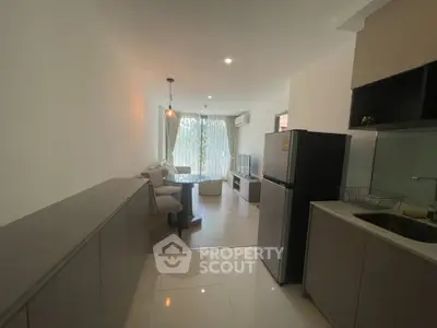 Modern living room with open kitchen, featuring sleek furniture and natural light.