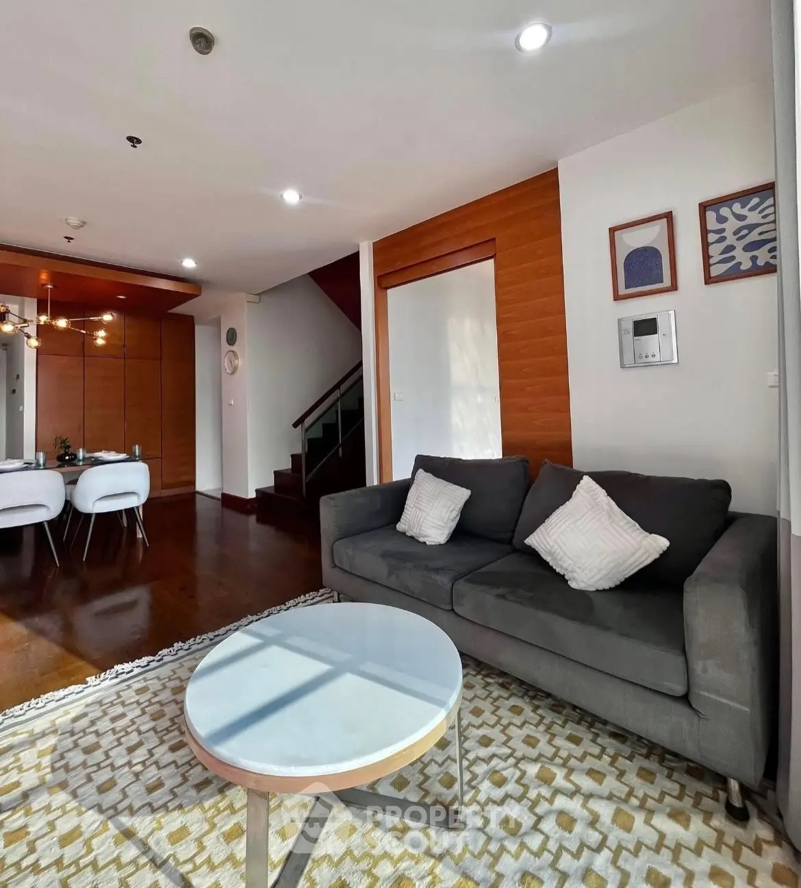 Spacious living room with modern decor and dining area, featuring stylish furniture and warm lighting.