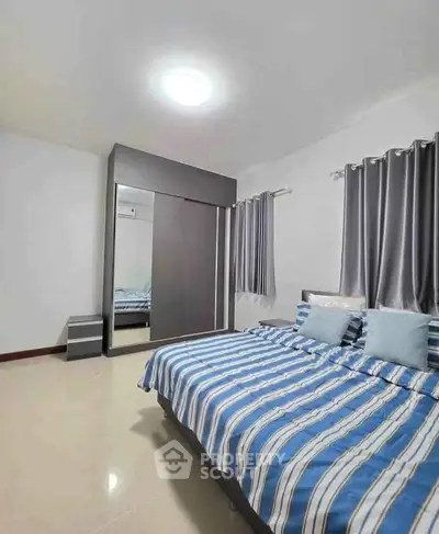 Spacious bedroom with modern decor and ample natural light, featuring a large bed and stylish curtains.