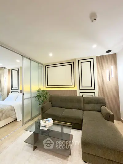 Modern living room with stylish decor and glass partition leading to bedroom