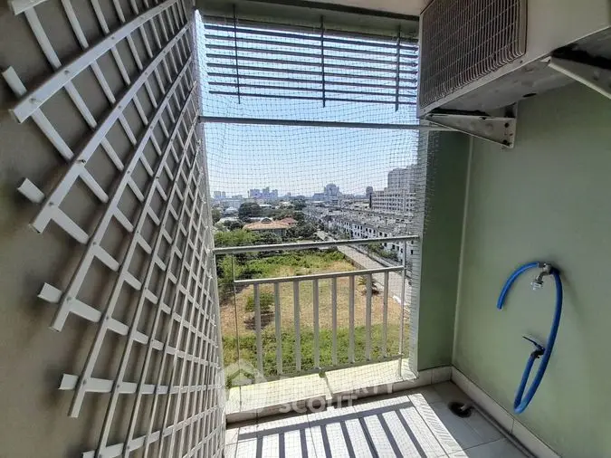 Spacious balcony with urban view, featuring safety railing and tiled floor, perfect for outdoor relaxation in a bustling city environment.
