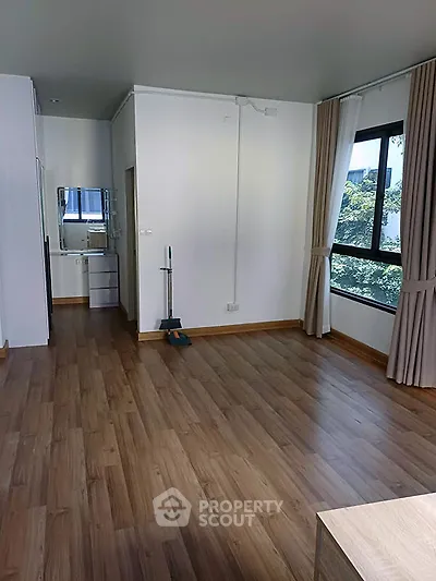 Spacious modern living room with wooden flooring and large windows offering natural light.