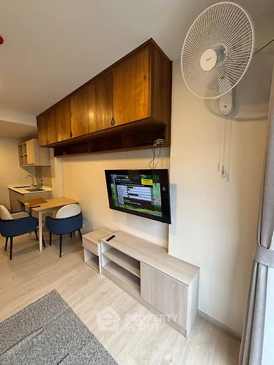 Modern living room with wall-mounted TV and stylish dining area in open layout apartment.