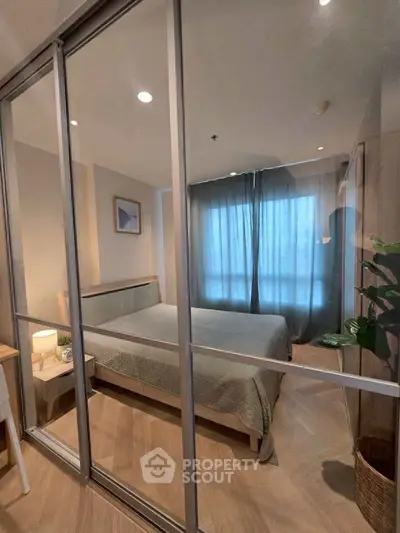 Modern bedroom with glass sliding doors and cozy decor in a stylish apartment.