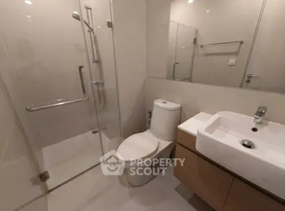 Modern bathroom with glass shower and sleek fixtures in contemporary apartment.