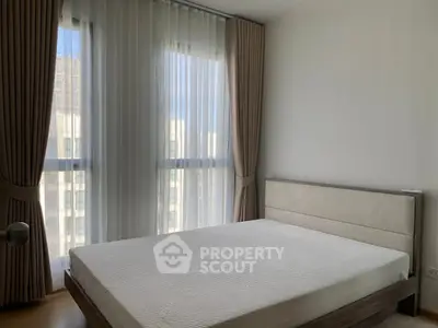 Modern bedroom with large windows and elegant curtains in a high-rise apartment.