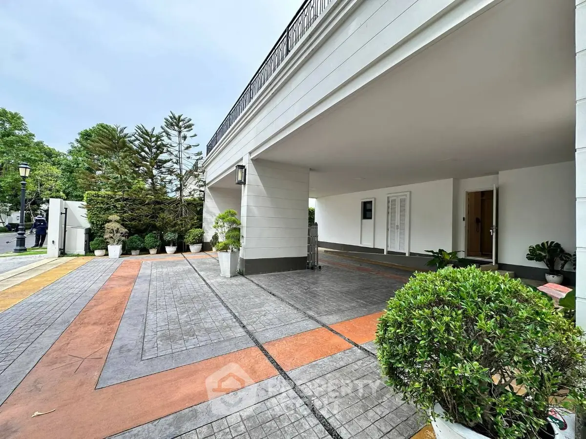 Elegant modern building entrance with spacious driveway and lush greenery