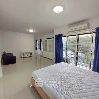 Spacious bedroom with large windows and modern furnishings in a bright apartment.