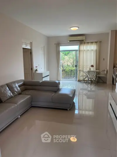Spacious living room with modern leather sofa and garden view, perfect for relaxation and entertaining.