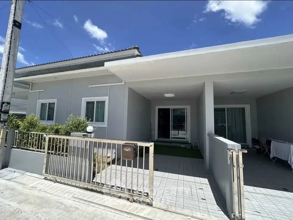 Modern single-story house with clean facade and gated entrance under clear blue sky.