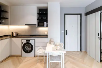 Modern kitchen with washing machine and dining area in stylish apartment