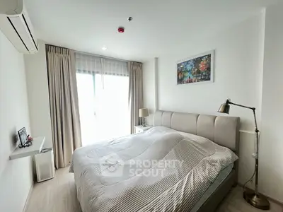 Bright and cozy bedroom with modern decor and large window for natural light.