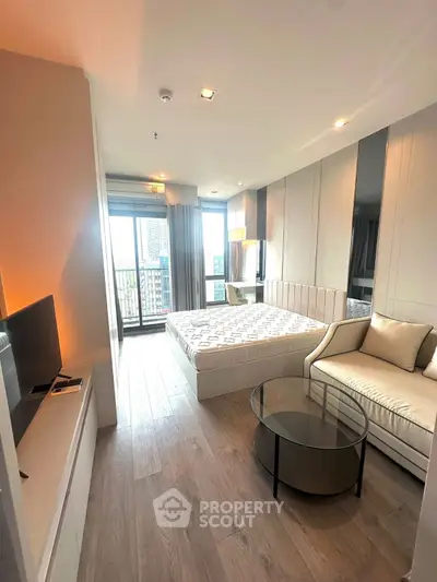 Modern bedroom with large windows and city view, featuring a cozy sofa and sleek furnishings.
