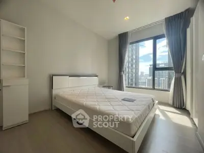 Modern bedroom with large window offering stunning city views, featuring a sleek white bed and minimalist decor.