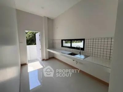 Modern kitchen with sleek design and natural light, featuring a minimalist open layout and tiled backsplash.