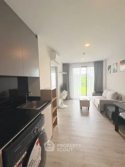 Modern living room with kitchenette, featuring sleek design and natural light, perfect for urban living.