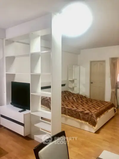 Spacious bedroom with modern shelving and cozy decor in a stylish apartment.