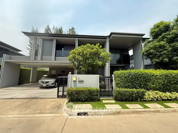 Modern two-story house with sleek design and lush greenery in a serene neighborhood.