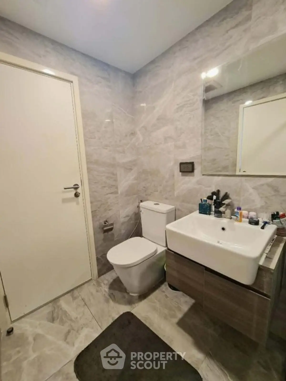 Modern bathroom with sleek fixtures and marble walls, featuring a stylish sink and toilet.