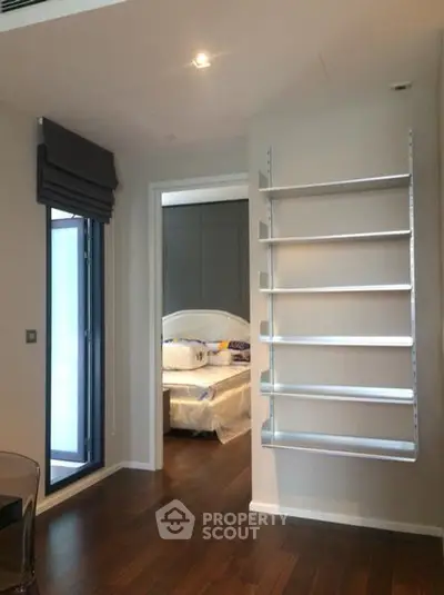 Modern bedroom with sleek shelving and hardwood floors in a stylish apartment.