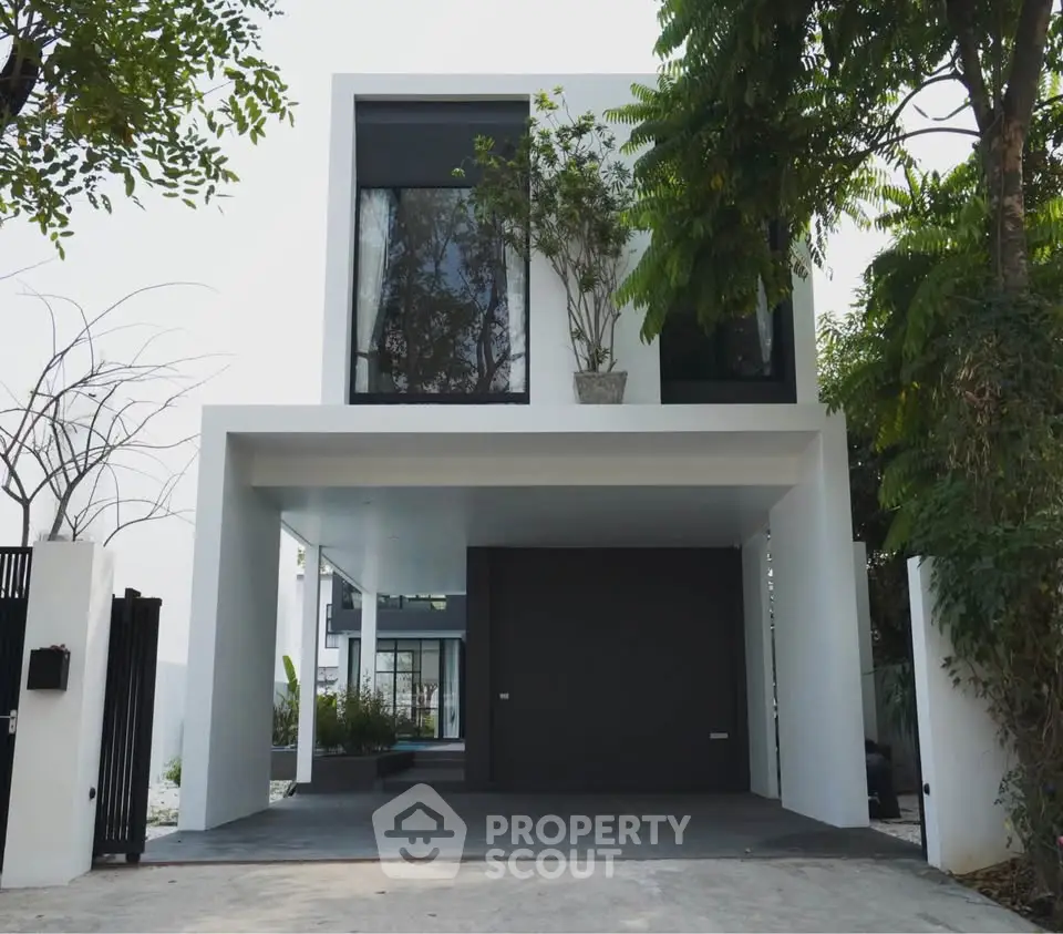 Modern minimalist two-story house with sleek design and lush greenery