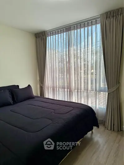Cozy bedroom with large window and elegant curtains, featuring a comfortable bed and stylish decor.