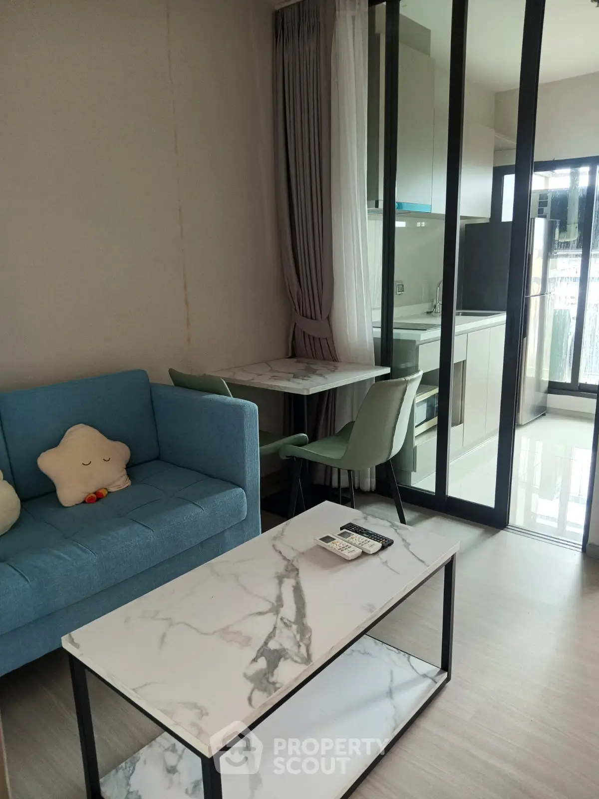 Modern living room with marble coffee table and compact kitchen in open layout apartment.