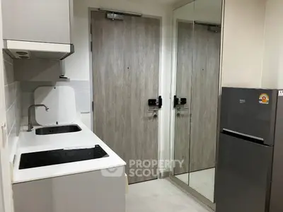 Compact modern kitchen with sleek appliances and mirrored wall for spacious feel.