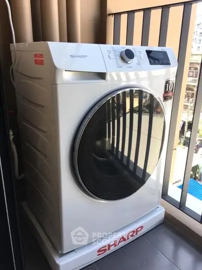 Modern Sharp washing machine on a balcony with city view, perfect for urban living convenience.