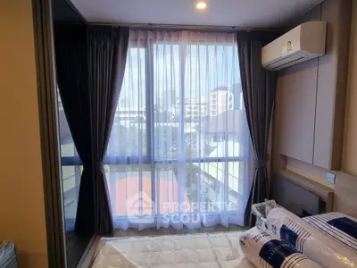 Modern bedroom with large windows and city view, featuring sleek curtains and air conditioning.