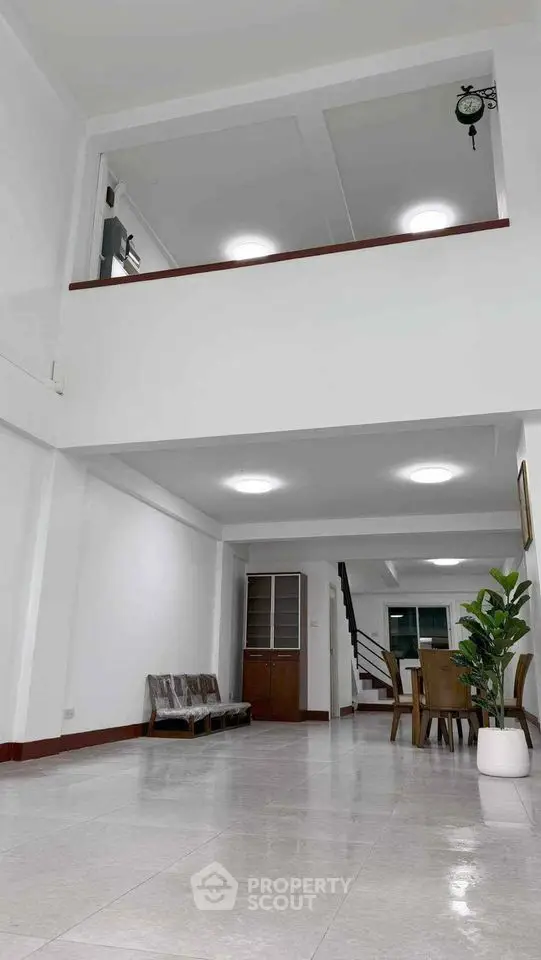 Spacious two-story living area with modern dining set and indoor plant